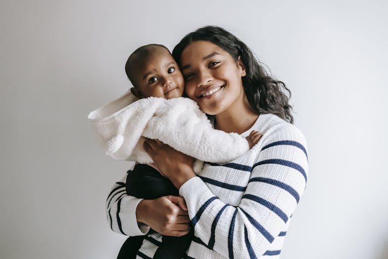 A joyful mother holds her smiling baby in a cozy indoor setting.